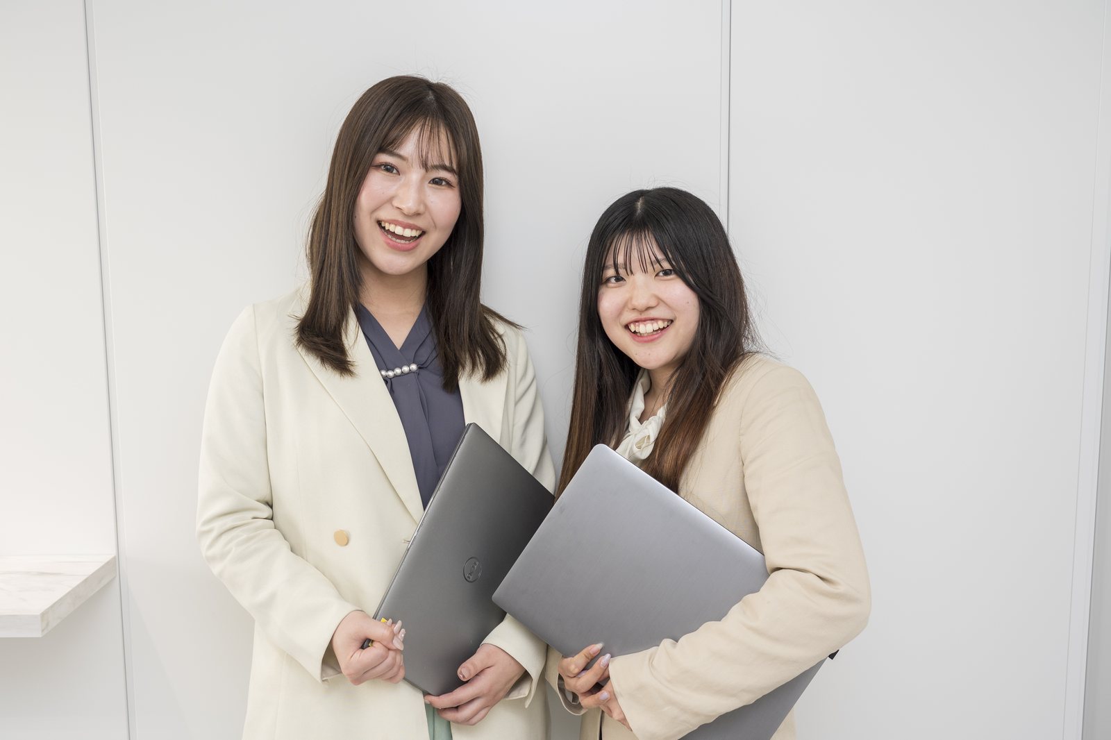ノートパソコンを手に笑顔で並ぶ営業・広報のスタッフ