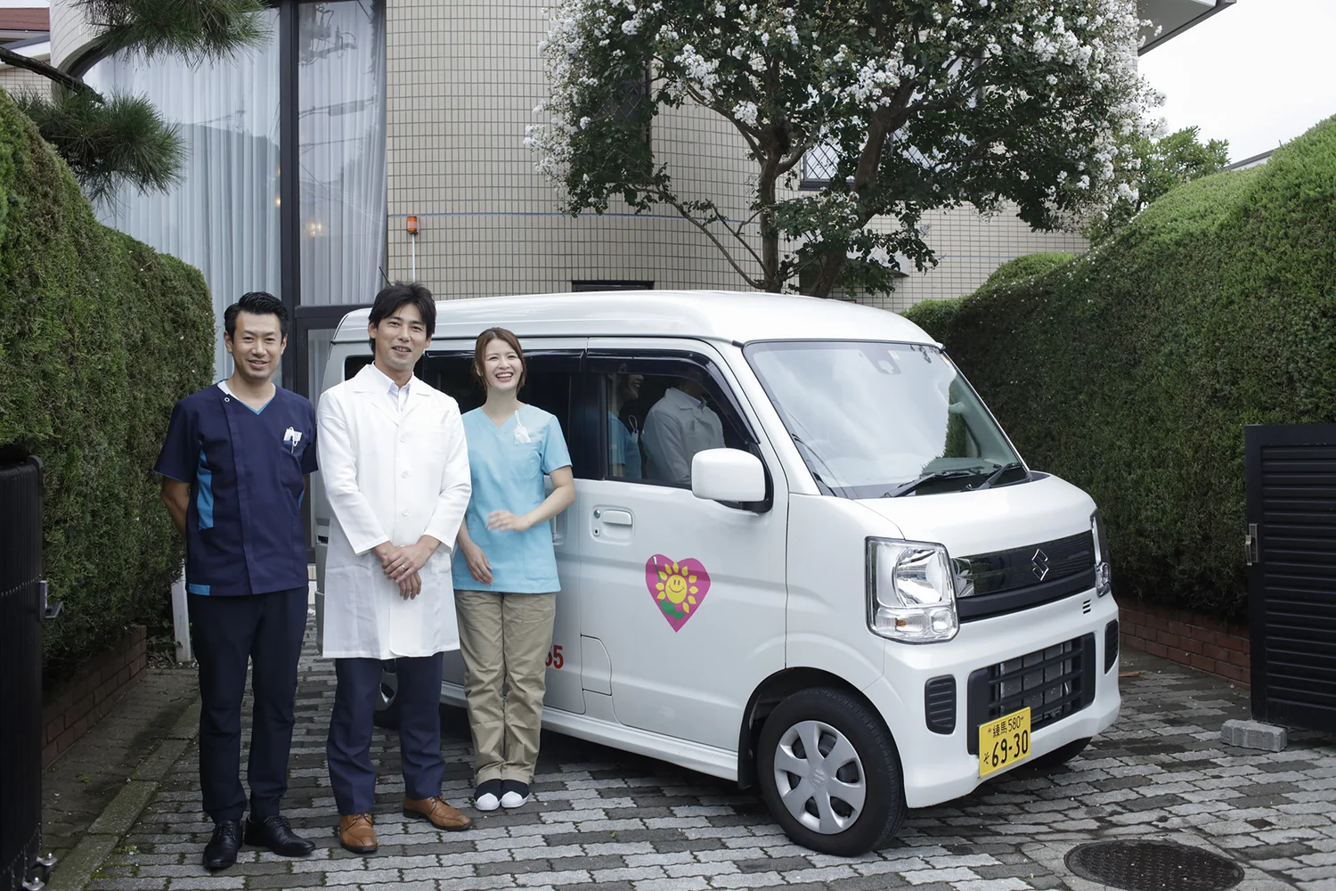 訪問車の前に立つ3人1組の訪問チーム
